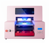 Image of a pastel pink ultraviolet printing machine, featuring an open printing bed, red internal mechanism, and a digital control panel. Designed for high-resolution direct-to-material printing on items like phone cases, leather accessories, and art prints, this machine offers small businesses a vibrant and efficient solution for professional ultraviolet printing projects