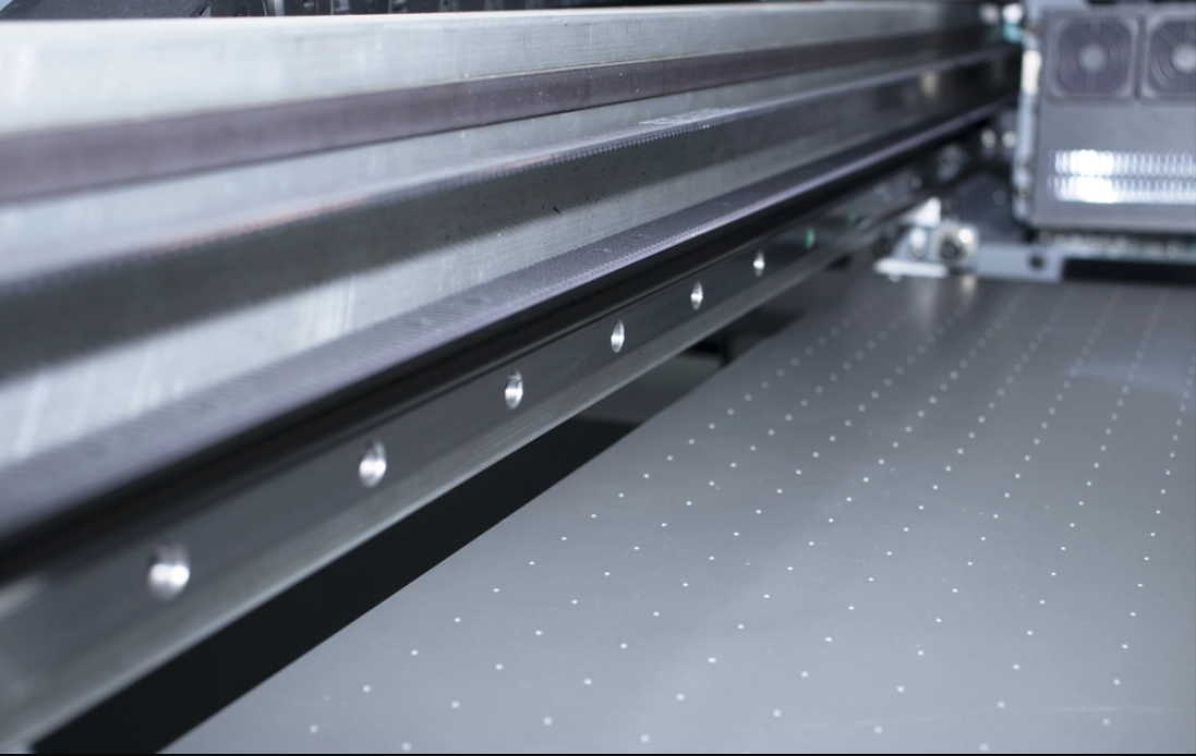 This image showcases the advanced flatbed transmission system of a UV printing machine, designed for uncompromised quality. Driven by a high-torque servo motor, it eliminates belt-driven inconsistencies and ensures exceptional positional accuracy. When paired with On-Demand Piezo electric printheads, the system delivers superior gradient smoothness and precise dot placement, making the UV machine for printing highly reliable for professional, high-resolution applications