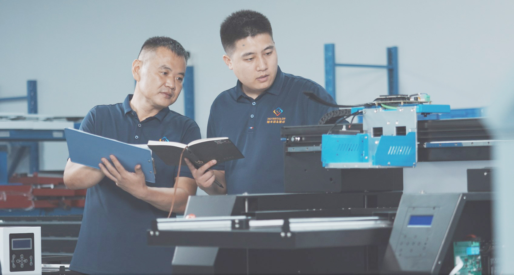 This image shows two engineers carefully inspecting and discussing technical details while observing a UV machine for printing. One holds a notebook and the other references documents, reflecting a structured approach to quality assurance and performance evaluation. The scene emphasizes precision, teamwork, and a strong commitment to ensuring reliable and efficient operation of advanced UV printing equipment.