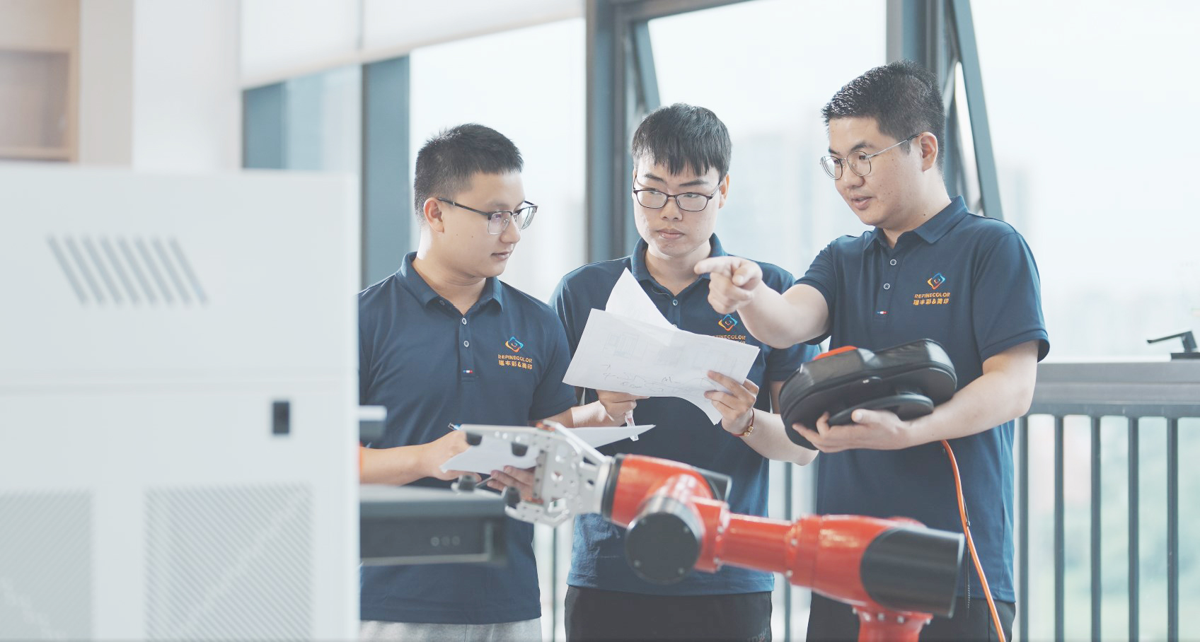 Image of engineers developing China LED UV printer technology, collaborating on designs and robotic integration. Highlights the technical innovation and expertise behind high-performance China LED UV printing equipment.